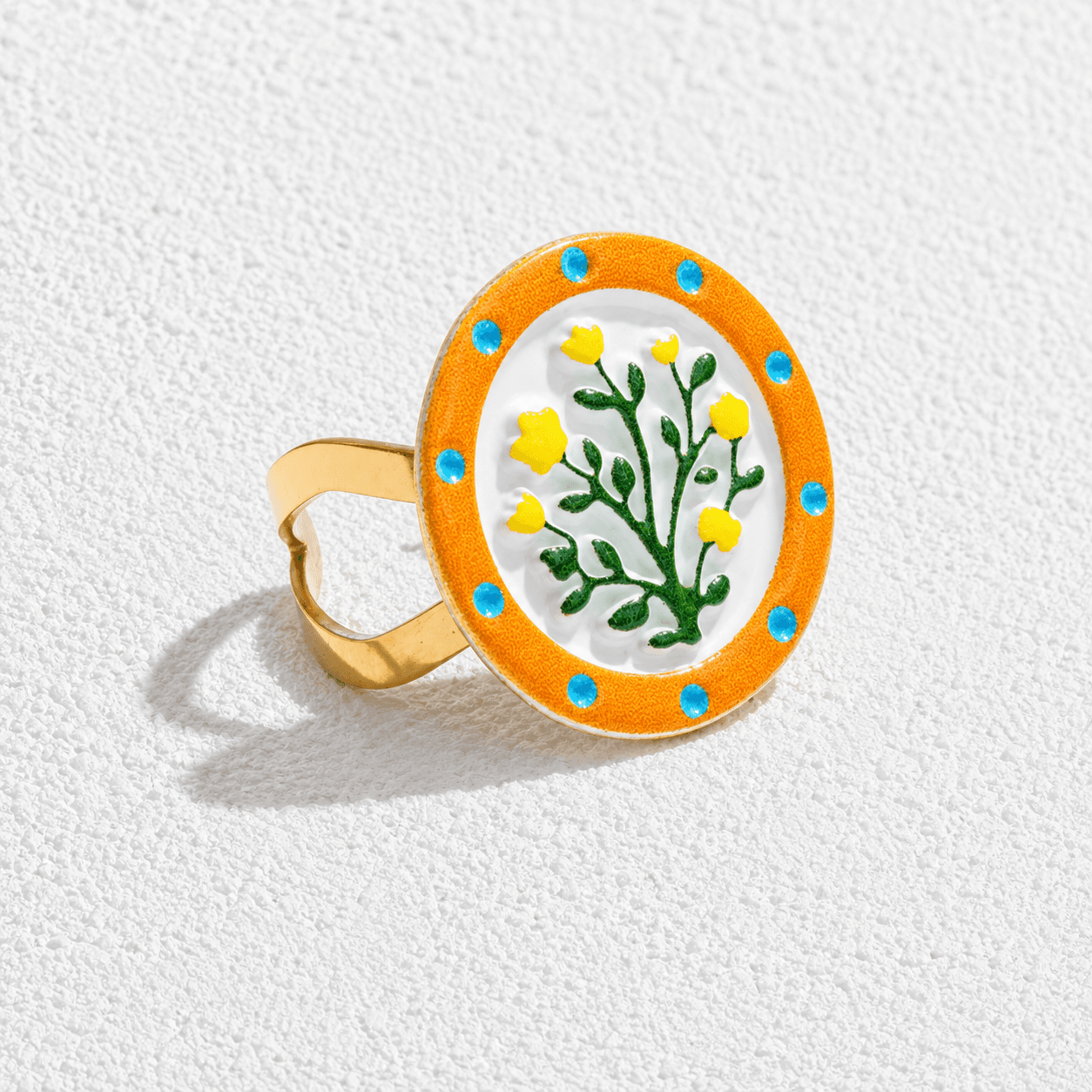 FLOR DE TAJINASTE · Anillo de esmalte ovalado con motivo floral amarillo y marco naranja.