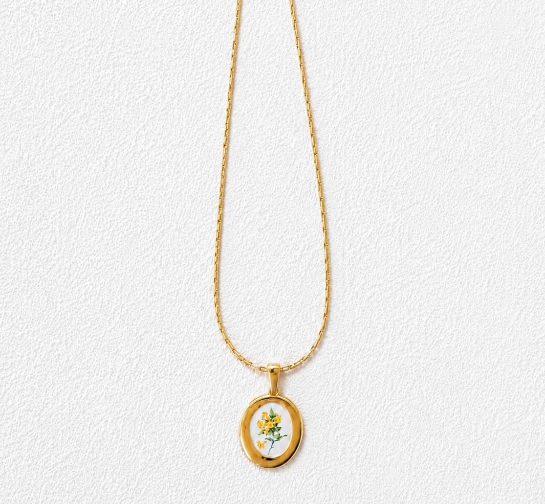 RETAMA DEL TEIDE · Collar de cadena rectangular con medallón ovalado y motivo floral amarillo