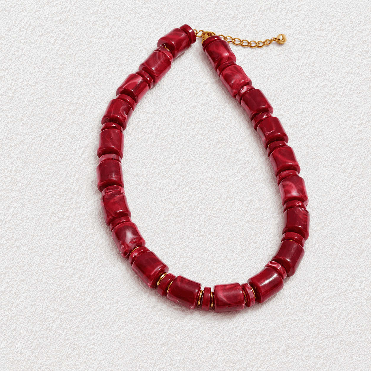 SANGRE DE DRAGO · Collar de cuentas cilíndricas rojas con separadores dorados.