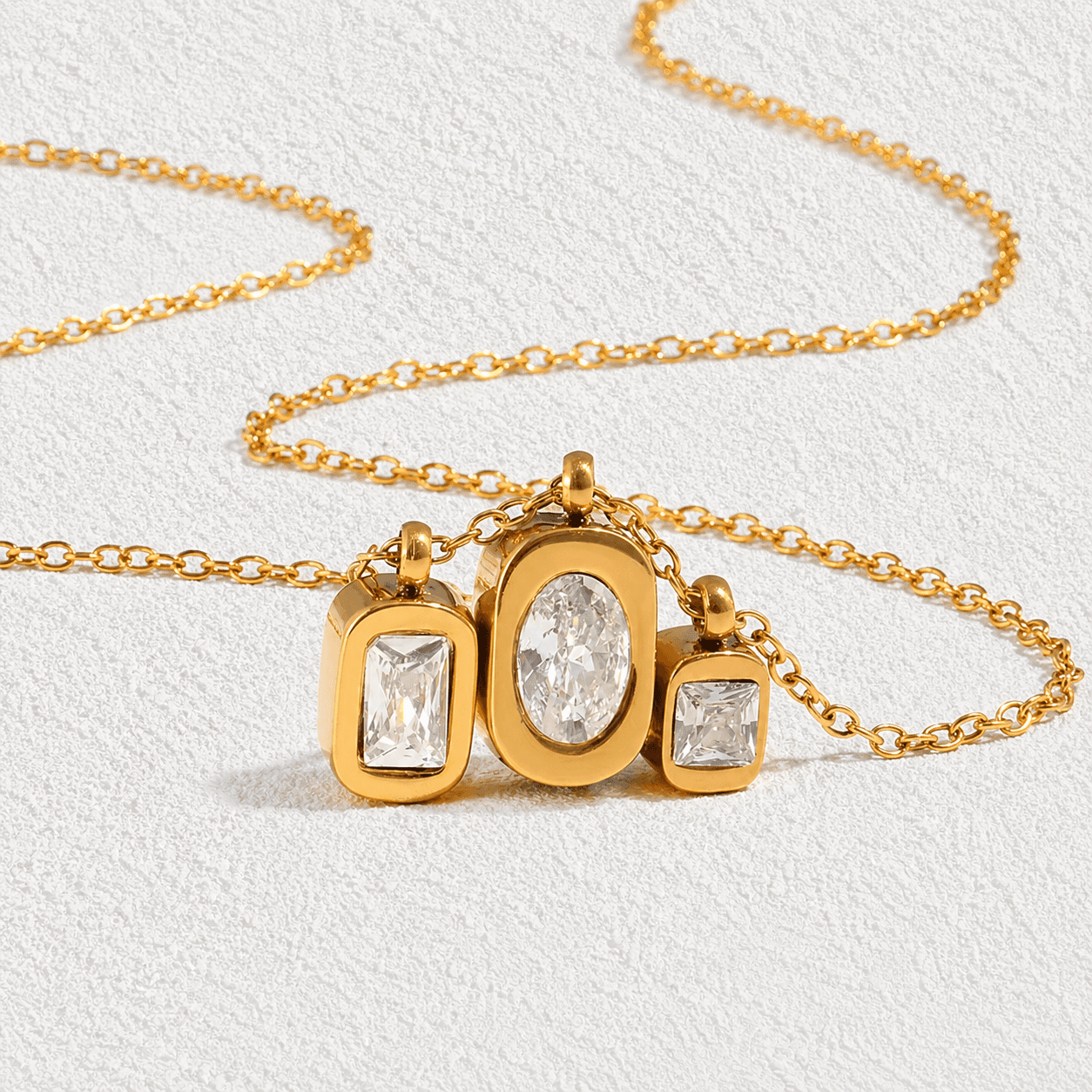 TRES ISLAS · Collar de cadena fina con triple colgante de cristales en distintas formas.